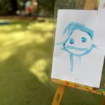 A child's blue face drawing on an easel.