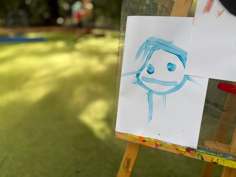 A child's blue face drawing on an easel.